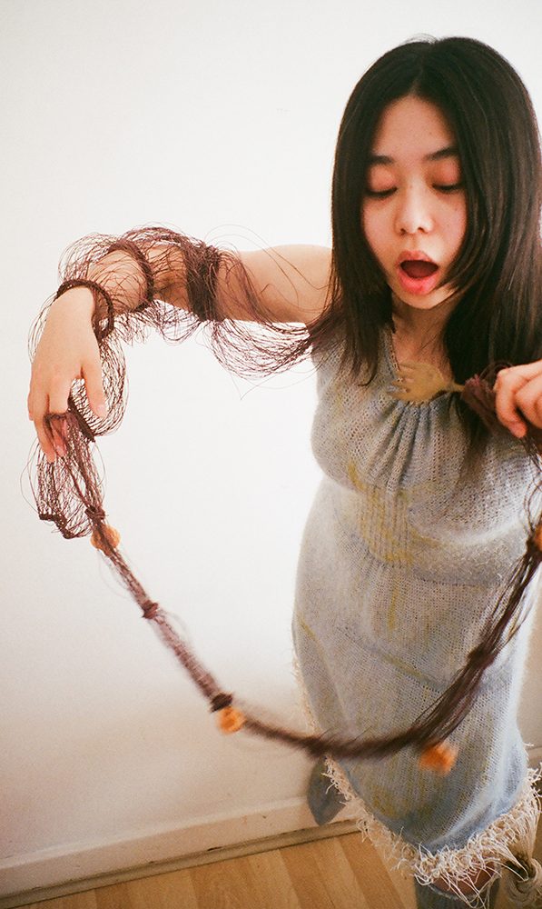 A woman in a blue-grey knitted dress with a long brown thread sleeve
