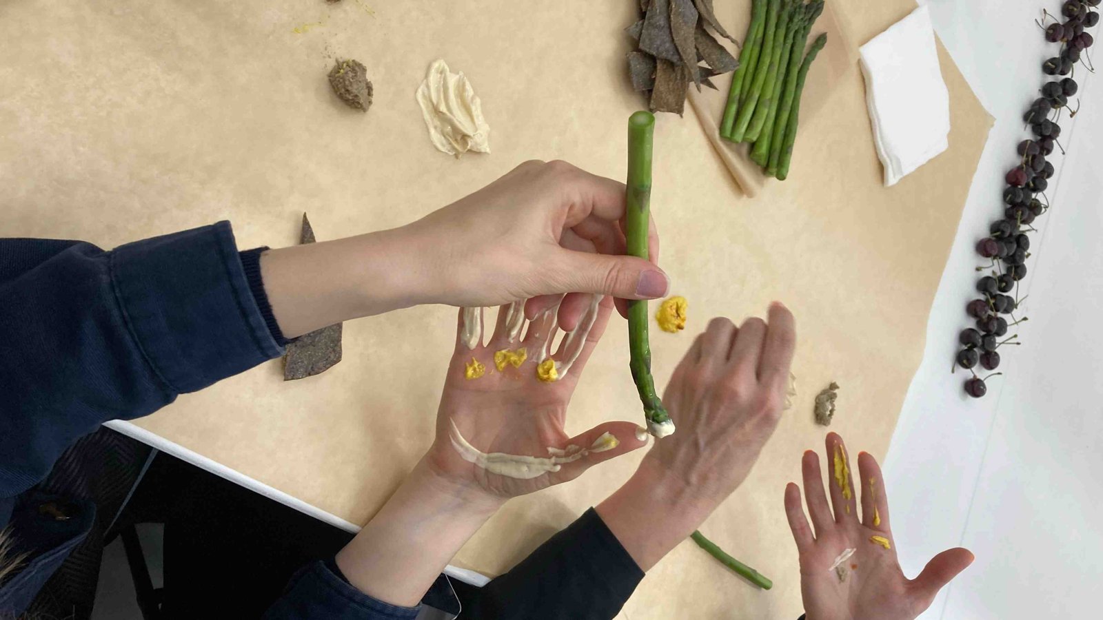 Close view of hands holding a green bean over a palm painted with yellow edible paint