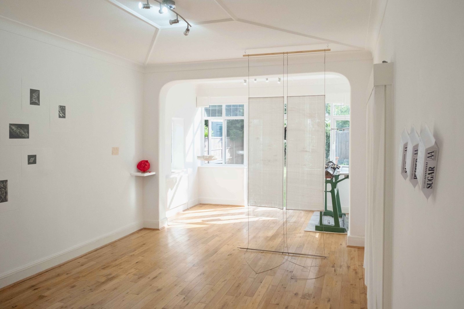 Gallery room with small framed works on the walls and the cat hat on a shelf