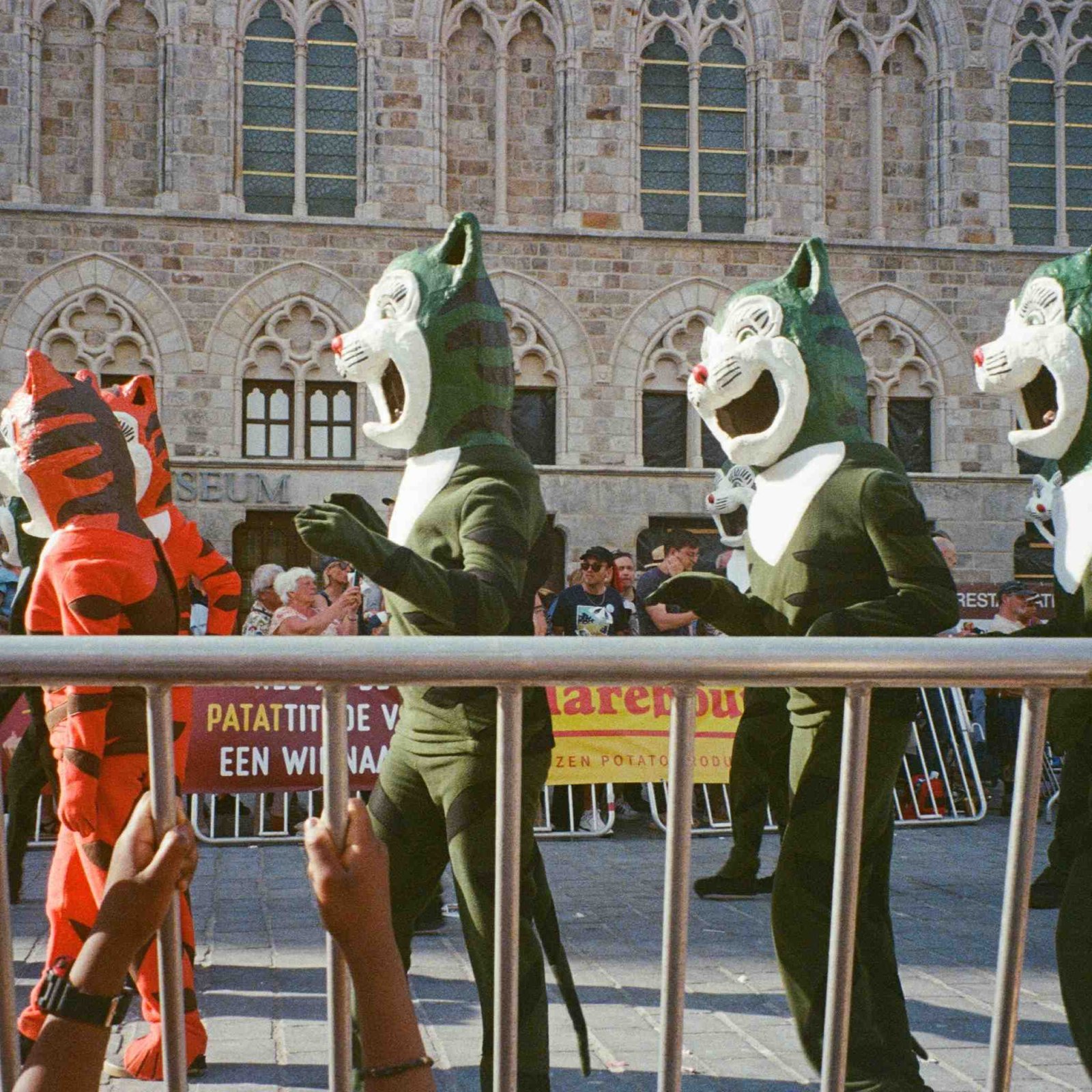 Cat-headed costumed figures in a street parade in front of a historic building